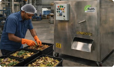 Operator preparing segregated food waste beside a COMPOSTO compost machine at a live installation